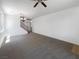 A spacious living room with gray carpet, a ceiling fan, lots of light, and stairs leading to the 2nd story at 8253 Pearl Oasis Ct, Las Vegas, NV 89139