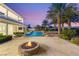 Stunning backyard featuring a pool, lush palm trees, a cozy fire pit, and travertine pavers, creating an outdoor oasis at 8895 S Tenaya Way, Las Vegas, NV 89113