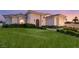 Beautiful home featuring a well-manicured lawn, lush green bushes, and an elegant front entrance at dusk at 8895 S Tenaya Way, Las Vegas, NV 89113