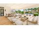 Covered patio with travertine floors, outdoor seating, and a view of the lushly landscaped pool area at 8895 S Tenaya Way, Las Vegas, NV 89113