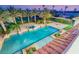 Aerial view of a pristine pool with tile flooring, surrounded by lush landscaping, including palms, at dusk at 8895 S Tenaya Way, Las Vegas, NV 89113