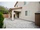 Covered back patio with pavers, trimmed bushes, brick wall, and a peaked roof at 9144 Clear Sky Ave, Las Vegas, NV 89178
