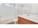 A well-lit bathroom with a combined bathtub and shower, a white vanity, and wood-look flooring at 928 Shades End Ave, North Las Vegas, NV 89081