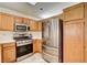 Kitchen with wood cabinets, stainless appliances, and tile backsplash at 931 Highland Trails Ave, Henderson, NV 89015