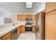 Well-lit kitchen showcasing stainless steel appliances, wood cabinets, and tile flooring at 931 Highland Trails Ave, Henderson, NV 89015