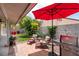 Relaxing backyard patio area with seating, a red umbrella, a grill, and manicured landscaping at 9329 Mountain Cliffs Ave, Las Vegas, NV 89129
