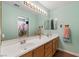 Well-lit bathroom features a dual sink vanity, large mirror, and separate shower with a vibrant floral shower curtain at 9329 Mountain Cliffs Ave, Las Vegas, NV 89129