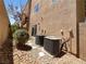 Home's backyard featuring air conditioning units and desert landscaping with rock and boulder accents at 9384 Hosner St, Las Vegas, NV 89178