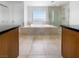 Bathroom featuring a soaking tub, tile flooring, glass-enclosed shower, and dual sinks with black countertops at 9384 Hosner St, Las Vegas, NV 89178