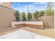 This backyard features a bench seating area with trees and greenery in the planter at 9713 Kampsville Ave, Las Vegas, NV 89148