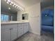 Bathroom featuring double sinks, ample storage in white cabinets, tile flooring and a bright vanity mirror at 1030 Country Skies Ave, Las Vegas, NV 89123
