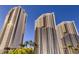 Striking exterior view showcasing the luxury high-rise condo buildings against a clear blue sky with lush greenery at 125 E Harmon Ave # 2718, Las Vegas, NV 89109