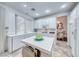 Bright kitchen featuring white cabinets, tile countertops, and an island, seamlessly flowing into the dining area at 1367 Minuet St, Henderson, NV 89052