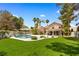 Lush backyard featuring a sparkling pool, verdant lawn, mature trees, and covered outdoor area at 1990 Freeman Ct, Henderson, NV 89014