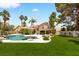 Expansive backyard featuring a sparkling pool, lush green lawn, and inviting lounge area at 1990 Freeman Ct, Henderson, NV 89014