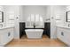Modern bathroom with a freestanding tub, double vanity with white cabinets, black fixtures, and plantation shutters at 1990 Freeman Ct, Henderson, NV 89014