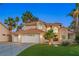 Elegant two-story home featuring a three-car garage, tile roof, manicured lawn, and lush palm trees at 1990 Freeman Ct, Henderson, NV 89014