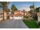 Elegant two-story home featuring a three-car garage, tile roof, manicured lawn, and lush palm trees at 1990 Freeman Ct, Henderson, NV 89014