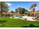 A pristine pool sits amongst green lawn and foliage, creating an oasis for relaxation and outdoor enjoyment at 1990 Freeman Ct, Henderson, NV 89014