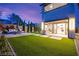 A twilight view of the backyard featuring artificial turf, patio space, and outdoor kitchen at 2407 Ridgeline Wash St, Las Vegas, NV 89138