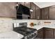 Close-up of the kitchen featuring stainless steel gas range, hood vent, stylish backsplash, and quartz countertops at 2407 Ridgeline Wash St, Las Vegas, NV 89138
