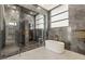 The luxurious bathroom showcases a glass shower, tub, and stone-tiled walls at 2695 Ponte Vecchio Ter, Henderson, NV 89052
