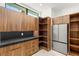 A modern pantry features sleek wood cabinets, a black countertop, and stainless steel refrigerator at 2695 Ponte Vecchio Ter, Henderson, NV 89052