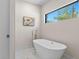Freestanding soaking tub with modern fixtures, framed artwork, and a window view at 3104 Conners Dr, Las Vegas, NV 89107