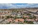 An aerial shot showcases a neighborhood with tile-roofed homes, palm trees, and a distant city skyline under a partly cloudy sky at 3236 Cliff Sieler Ct, Las Vegas, NV 89117