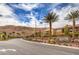 Inviting community entrance with lush landscaping, palm trees, and a decorative stone sign under a bright blue sky at 3486 Molinos Dr, Las Vegas, NV 89141