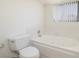 Bathroom with a white jetted bathtub, toilet, and window with natural light at 3972 Tirana Way, Las Vegas, NV 89103