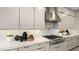 Modern kitchen features gas range with stainless steel vent hood, light quartz countertops, and herringbone backsplash at 489 Carter House Way, Las Vegas, NV 89138