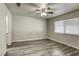 A bright bedroom features wood-look floors, ceiling fan, and window with blinds at 5132 Springland St, Las Vegas, NV 89146