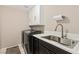 Efficient laundry room equipped with modern washer and dryer, and a sink with stylish fixtures at 6013 Jubilee Gardens Ave, Las Vegas, NV 89131