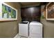 Functional laundry room with front load machines, upper cabinets and wine rack for convenient storage at 606 Cadence Vista Dr, Henderson, NV 89011