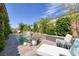 Inviting backyard with a pool, stone waterfall feature, lush landscaping, and comfortable lounge chairs at 606 Cadence Vista Dr, Henderson, NV 89011