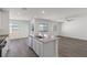 Open floor plan with kitchen island, wood floors, and large windows filling the room with natural light at 6787 Magnolia River Ave, Las Vegas, NV 89156