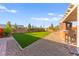 Expansive backyard with lush artificial turf, outdoor kitchen area, and mature trees for shade and privacy at 6980 W Meranto Ave, Las Vegas, NV 89178