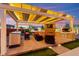 Outdoor kitchen and living area with built in barbecue, tv, bar seating and lounge at 6980 W Meranto Ave, Las Vegas, NV 89178