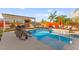 Backyard pool features a built-in grill, outdoor seating, and surrounding palm trees for relaxation at 6980 W Meranto Ave, Las Vegas, NV 89178