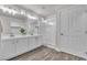A modern bathroom features a double vanity, frameless shower and wood-look floors at 7820 Milkweed Ct, Las Vegas, NV 89149