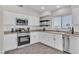 Bright kitchen featuring white cabinets, stainless steel appliances, subway tile backsplash, and wood-look flooring at 7820 Milkweed Ct, Las Vegas, NV 89149