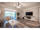 Cozy living room with wood floors, a ceiling fan, a large window, and a modern entertainment center at 8 Via Dolcetto, Henderson, NV 89011