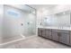 Bathroom featuring a large glass shower with a bench and a double vanity with gray cabinetry at 9314 Observatory St, Las Vegas, NV 89143
