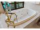 Close-up of luxurious soaking tub with gold fixtures, and tile surround at 1 Hughes Center Dr # 308, Las Vegas, NV 89169