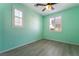 Charming bedroom with mint-green walls, wood-look floors, ceiling fan, and two windows at 11238 Meadow Cove St, Las Vegas, NV 89179