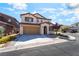 Two-story tan house with a two-car garage, arched entryway and a well-maintained front yard at 11238 Meadow Cove St, Las Vegas, NV 89179