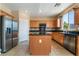 Spacious kitchen featuring stainless steel appliances, granite countertops, wood cabinetry, and tile floors at 11238 Meadow Cove St, Las Vegas, NV 89179