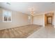 Spacious living room featuring neutral walls, carpet and tile flooring, large windows, and an elegant chandelier at 11238 Meadow Cove St, Las Vegas, NV 89179