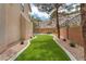 Backyard with artificial grass, mature trees, and rock wall landscaping at 1155 Phillip Island St, Henderson, NV 89052